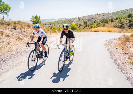 Die ganze Länge der Radfahrer in Sportbekleidung und Helme zusammen Radfahren Auf asphaltierter Fahrbahn im Sommer auf dem Land Stockfoto
