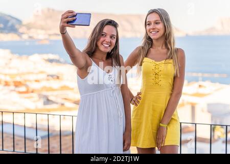 Optimistische Millennial Freundinnen umarmen und Selfie auf dem Handy nehmen Telefonieren Sie, während Sie Sommerferien zusammen in Küstenstadt in der Nähe verbringen Meer Stockfoto