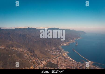 Luftaufnahme eines Teils der modernen Flugzeuge fliegen über erstaunlich Bergige und küstennahe Hafenlandschaft am Morgen auf Teneriffa Stockfoto