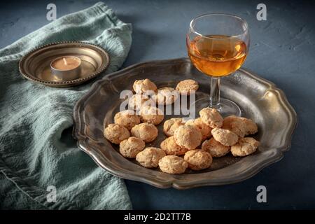 Amaretto Likör und Amaretto Kekse auf einem dunklen Tisch, launisches Stillleben Stockfoto