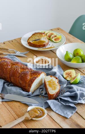 Draufsicht Zusammensetzung von geschnittenem geflochtenem Brot serviert mit frischem Feigen und süße Fruchtkonfitüre auf Holztisch Stockfoto