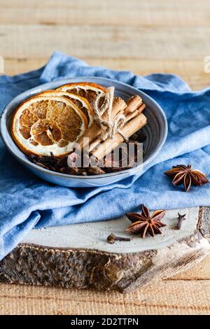 Hoher Winkel der Schüssel mit aromatischen Zimtstangen und getrocknet Orangen auf dem Tisch mit Sternanis und Nelken angeordnet Stockfoto