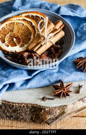 Hoher Winkel der Schüssel mit aromatischen Zimtstangen und getrocknet Orangen auf dem Tisch mit Sternanis und Nelken angeordnet Stockfoto