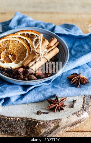 Hoher Winkel der Schüssel mit aromatischen Zimtstangen und getrocknet Orangen auf dem Tisch mit Sternanis und Nelken angeordnet Stockfoto
