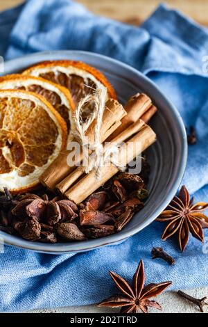 Hoher Winkel der Schüssel mit aromatischen Zimtstangen und getrocknet Orangen auf dem Tisch mit Sternanis und Nelken angeordnet Stockfoto