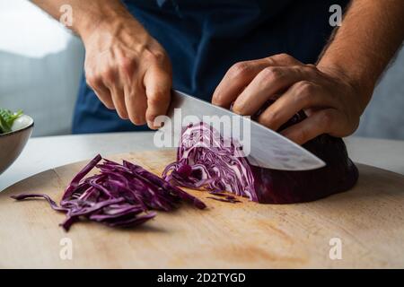 Crop anonyme kochen Hacken frischen natürlichen Rotkohl auf Holz Schneidebrett während der Zubereitung gesunder Gerichte in der Küche Stockfoto