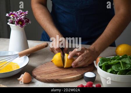 Crop anonymen männlichen Koch Schneiden frische Zitrone auf Holzbrett Während der Zubereitung gesunder Gerichte mit natürlichen Zutaten in der Küche Stockfoto