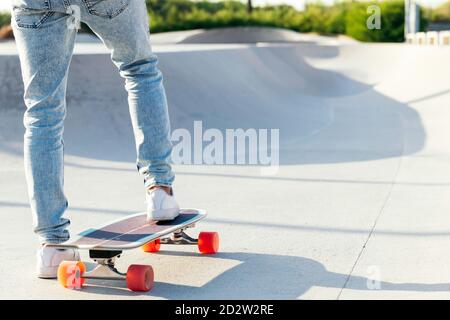 Unerkennbarer stylischer Skater in Jeans und Sneakers auf Skateboard stehend Im Skatepark an sonnigen Tag im Sommer Stockfoto