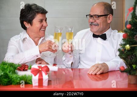 Seniorenpaar feiert weihnachten Klappern Gläser Champagner und lächelnd. Weihnachtsfeier Konzept. Stockfoto