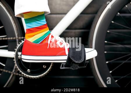 Unerkennbare Crop Person trägt bunt gestreiften Socken sitzen auf modern Fahrrad in der Stadt Stockfoto