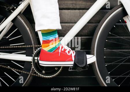 Unerkennbare Crop Person trägt bunt gestreiften Socken sitzen auf modern Fahrrad in der Stadt Stockfoto