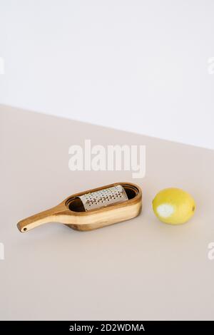 Frische ganze Zitrone auf dem Tisch mit scharfer Holzreibe angeordnet Im Studio auf zweifarbigem Hintergrund Stockfoto