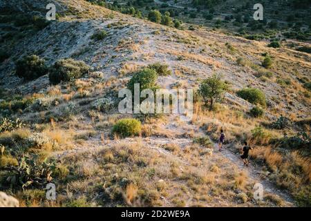 Von oben Rückansicht von anonymen Männchen und Weibchen in Sportbekleidung Laufen auf schmalen Pfad auf Hügel beim Training Trail Gemeinsam laufen Stockfoto