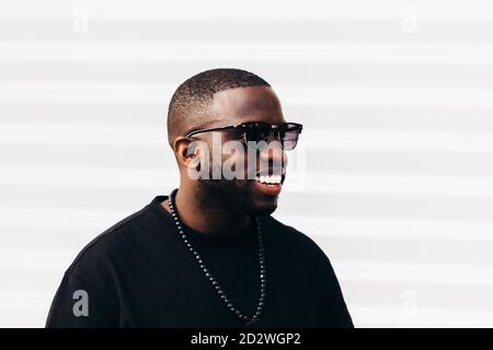 Glücklich schwarzen Mann posiert und lächelt über weißem Hintergrund und Schwarze Sonnenbrille tragen Stockfoto