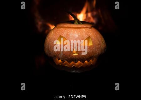 Gruseliger halloween Kürbis in der Nähe eines Kamins. Feuer auf dem Hintergrund. Stockfoto