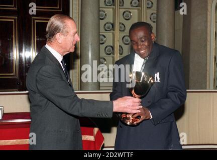 Der Herzog von Edinburgh, Patron und Zwölfter Mann, der wohltätigen Organisation The Lord's Taverners, überreicht dem Warwickshire Fast Bowler Gladstone Small (rechts) im Namen des gesamten Teams die Lord's Taverner's Trophy im Buckingham Palace. Stockfoto