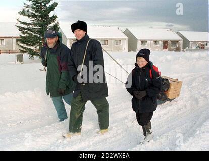 Brian Moulder, links, George Anderson und der junge Lee Moulder ziehen mit einem gefrorenen truthahn an Bord zu Freunden zum Weihnachtsessen, als Schnee und grauenhafte Wetterbedingungen heute (Montag) zu arktischen Szenen auf den Shetland-Inseln führten. DIESES MATERIAL IST FÜR REGIONALE UND AUSLÄNDISCHE ABONNENTEN KOSTENLOS, ABER IN LONDON ANSÄSSIGE STAATSANGEHÖRIGE UND ALLE SCHOTTISCHEN ZEITUNGEN WERDEN VOM FOTOGRAFEN GRAEME STORY IN LERWICK, SHETLAND ISLANDS GEGEN BEZAHLUNG ANGESPROCHEN. Stockfoto