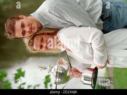 Der Snookerweltmeister Stephen Hendry hält die nächste Ankunft bei der Familie Hendry fest, während die schwangere Frau Mandy die Botschaftsweltpokertrophäe hält, die Stephen zum 6. Mal gewann. Stockfoto