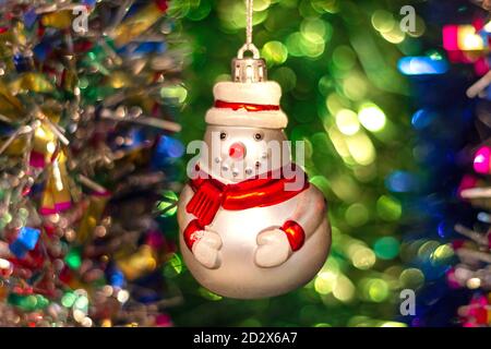 Vintage Glas Sowjetisches Neujahrsspielzeug (Schneemann) vor dem Hintergrund eines Weihnachtsbaums und farbenfroher heller Lametta. Stockfoto