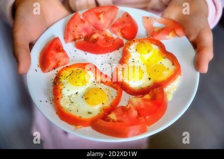 Eine Frau hält einen Teller Wachteleier mit Tomate Und Paprika Stockfoto