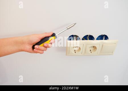 Hand mit Schraubendreher zur Reparatur von Steckdosen zu Hause Stockfoto