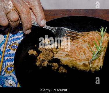 Shepherd's Pie einzelne Portion auf einem Teller. Man Hand mit einer silbernen Gabel, um einen Bissen von Schäferkuchen zu bekommen. Stockbild. Stockfoto