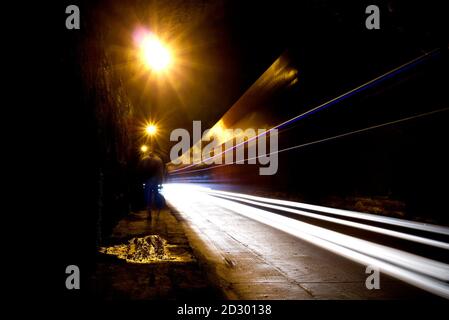 Verschwommenes Bild einer menschlichen Silhouette in einem Tunnel. Ein Mann, der ins helle Licht in Unschärfe geht. Stockfoto