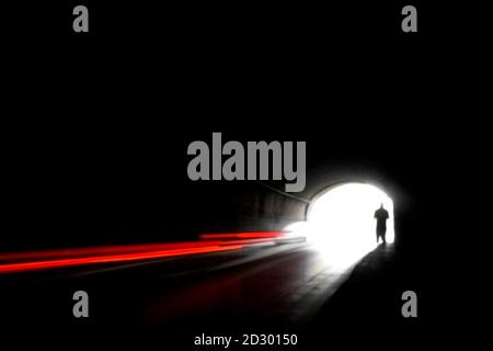 Verschwommenes Bild einer menschlichen Silhouette in einem Tunnel. Ein Mann, der ins helle Licht in Unschärfe geht. Stockfoto