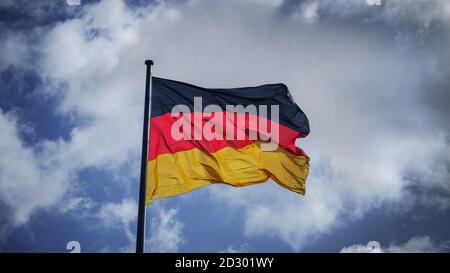 Deutschland Flagge mit dramatisch bewölktem Himmel auf dem Hintergrund Stockfoto