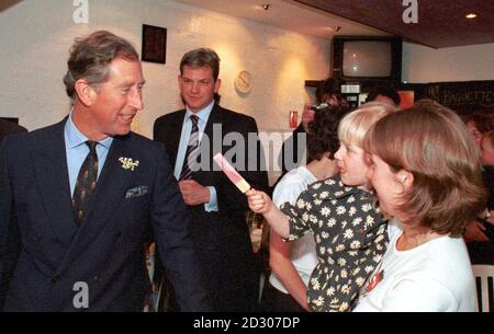 Die dreijährige Ashleigh Palmer bietet dem Prinzen von Wales während eines Besuchs des Prinzen im Zebedees Cafe in Truro, Cornwall, einen Leck ihrer Eislolle an. Stockfoto