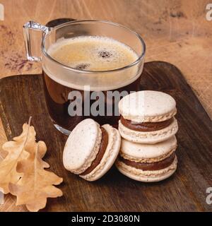 Tasse Kaffee und Schokoladenmakronen auf Holzhintergrund. Gemütliche Herbstkomposition. Quadrat - Bild Stockfoto