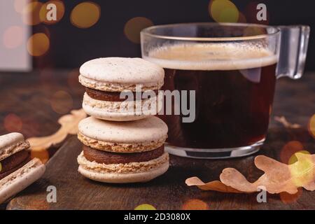Kaffee in Glastasse und Schokoladenmakronen auf Holzhintergrund. Gemütliche Herbstkomposition mit Bokeh-Effekt - Bild Stockfoto