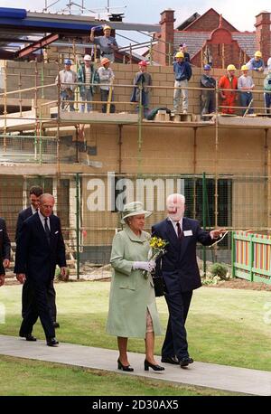 Die britische Königin Elizabeth und der Herzog von Edinburgh passieren eine Baustelle, während sie die Garston Village Hall in Liverpool während ihres Besuchs in der Stadt besuchen. Stockfoto