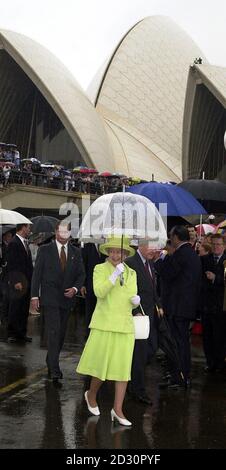 Die britische Königin Elizabeth II. Verwendet bei starkem Regen einen transparenten Regenschirm während der offiziellen Begrüßungszeremonie, bei der sie vom Generalgouverneur Sir William Deane (R) im Opernhaus von Sydney, Australien, begleitet wurde. Stockfoto