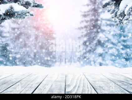 Holztischplatte auf Winter sonnige Landschaft mit Tannen. Frohe Weihnachten und frohes Neues Jahr Gruß Hintergrund. Winterlandschaft mit Schnee und Schnee Stockfoto