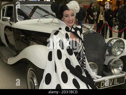 Die Filmfigur Cruella Devil kommt an der Waterloo Station in London an, um Disneys Eurostar-Zug „102 Dalmatiner“ zu starten. Alle achtzehn Reisebusse des Viertelmeile-Zuges sind mit Bildern dalmatinischer Welpen bedeckt. Stockfoto