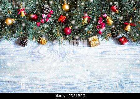 Tannenzweige mit Spielzeug auf altem Holztisch. Weihnachtskarte mit Dekoration. Stockfoto