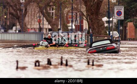 Ruderer von der Cambridge University fahren an der Themse am Putney Embankment vorbei und passieren ein versunkenes Auto in London, während sie an den Versuchen teilnehmen, um im Team für das nächste Jahr des University Boat Race gegen Oxford anzutreten. Stockfoto