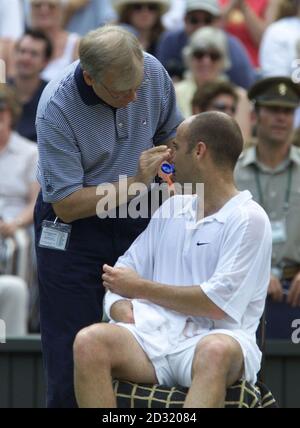 KEINE KOMMERZIELLE NUTZUNG: Andre Agassi aus den USA lässt sich während seines Spiels gegen den Australier Pat Rafter während des Halbfinals der Herren bei den Lawn Tennis Championships 2001 in Wimbledon in London Sonnencreme in die Nase reiben. Stockfoto