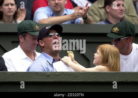 KEINE KOMMERZIELLE NUTZUNG: Der australische Cricketspieler Shane Warne (Mitte) spielt mit seiner Tochter, während er das Herrenfinale zwischen dem Australier Pat Rafter und dem Kroatischen Goran Ivanisevic bei den Lawn Tennis Championships 2001 in Wimbledon in London beobachtet. Stockfoto