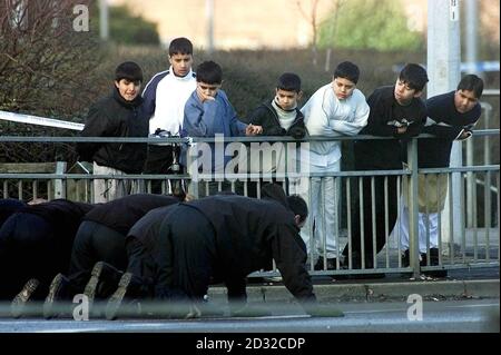 Eine Gruppe von Kindern beobachtet, wie Polizeibeamte die Gegend am Kreisverkehr in Keighley, West Yorkshire, durchsuchen, wo ein 24-jähriger Mann verfolgt und zu Tode geprügelt wurde, nachdem sein Auto von zwei anderen Autos gerammt wurde. Der Angriff ereignete sich um etwa 13/2/02 Uhr. * kurz nach dem Mann, fuhr weg von einem Freizeitzentrum in der Stadt. Die Polizei sagte heute, dass sie nicht glauben, dass der Angriff entweder rassistisch motiviert war oder ein versuchter Karjackversuch war. Stockfoto