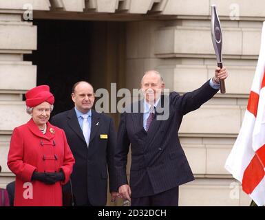 Königin Elizabeth II. Mit Charles Allen, dem Vorsitzenden von Manchester 2002, und Roger Bannister (rechts), die den Commonwealth-Stab halten, bei den Commonwealth Day-Feierlichkeiten auf dem Vorplatz des Buckingham Palace. In einem spektakulären Send-off, * mit Feuerwerk vom Dach des Buckingham Palace, Ballons und Mini-Pop-Konzert, übergab die Queen den Manchester Games Hi-Tech-Taktstock an Sir Roger, der erste Mann, der eine Meile in weniger als vier Minuten gelaufen ist. Es war der Starstart einer 58,000-Meilen-Staffel um die Welt, durch 23 Commonwealth-Länder und zurück nach Großbritannien für den Juli 25 Stockfoto