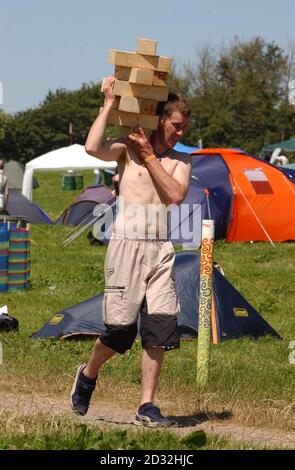 Ein Festivalbesucher trägt Feuerholz in Glastonbury, während sich die Menschen für die jährliche weltberühmte dreitägige Musikveranstaltung versammeln, die sich über 900 Hektar in Somerset erstreckt und voraussichtlich etwa 105,000 Menschen anziehen wird. * NatWest, die Bank, die Geldautomaten für die Festivals liefert, hat gesagt, dass die Geldautomaten auf dem Festival die Nutzung von Geldautomaten an belebten Londoner Bahnhöfen, Piccadilly Circus und Oxford Street übertreffen werden. Stockfoto