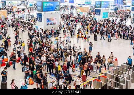 Massen von chinesischen Reisenden mit Schutzmasken warten in Warteschlangen an den Einstiegstoren des Shenzhen Nordbahnhofs, als sie den Nationalfeiertag in China beenden, der auch als die goldene Woche bekannt ist. Stockfoto