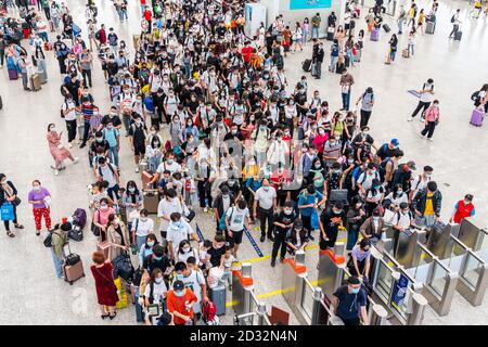 Massen von chinesischen Reisenden mit Schutzmasken warten in Warteschlangen an den Einstiegstoren des Shenzhen Nordbahnhofs, als sie den Nationalfeiertag in China beenden, der auch als die goldene Woche bekannt ist. Stockfoto
