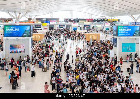 Massen von chinesischen Reisenden mit Schutzmasken warten in Warteschlangen an den Einstiegstoren des Shenzhen Nordbahnhofs, als sie den Nationalfeiertag in China beenden, der auch als die goldene Woche bekannt ist. Stockfoto