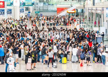 Massen von chinesischen Reisenden mit Schutzmasken warten in Warteschlangen an den Einstiegstoren des Shenzhen Nordbahnhofs, als sie den Nationalfeiertag in China beenden, der auch als die goldene Woche bekannt ist. Stockfoto