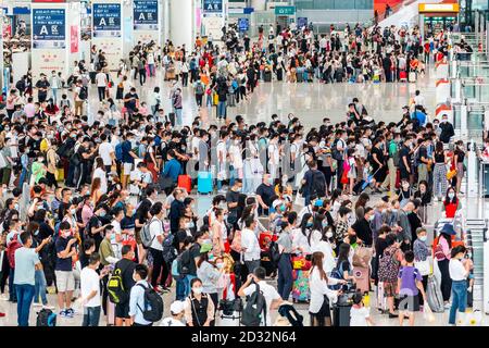 Massen von chinesischen Reisenden mit Schutzmasken warten in Warteschlangen an den Einstiegstoren des Shenzhen Nordbahnhofs, als sie den Nationalfeiertag in China beenden, der auch als die goldene Woche bekannt ist. Stockfoto