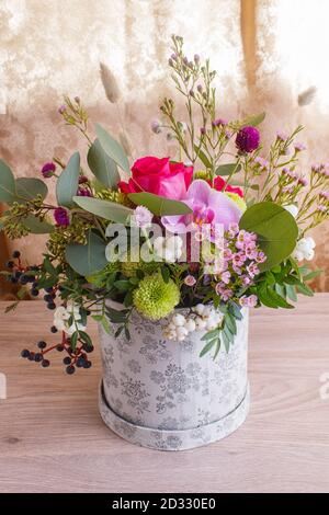 Komposition von Herbstblumen in einer Hutbox auf einem hölzernen Hintergrund. Floristische Anordnung. Stockfoto