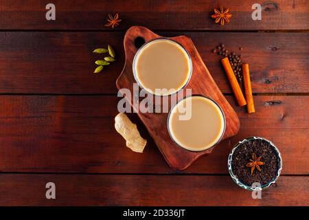 Milchtee und Gewürze. Masala Chai Tee auf Holzbrettern. Zwei Gläser Masala-Tee und Zutaten für die Herstellung. Speicherplatz kopieren. Draufsicht Stockfoto